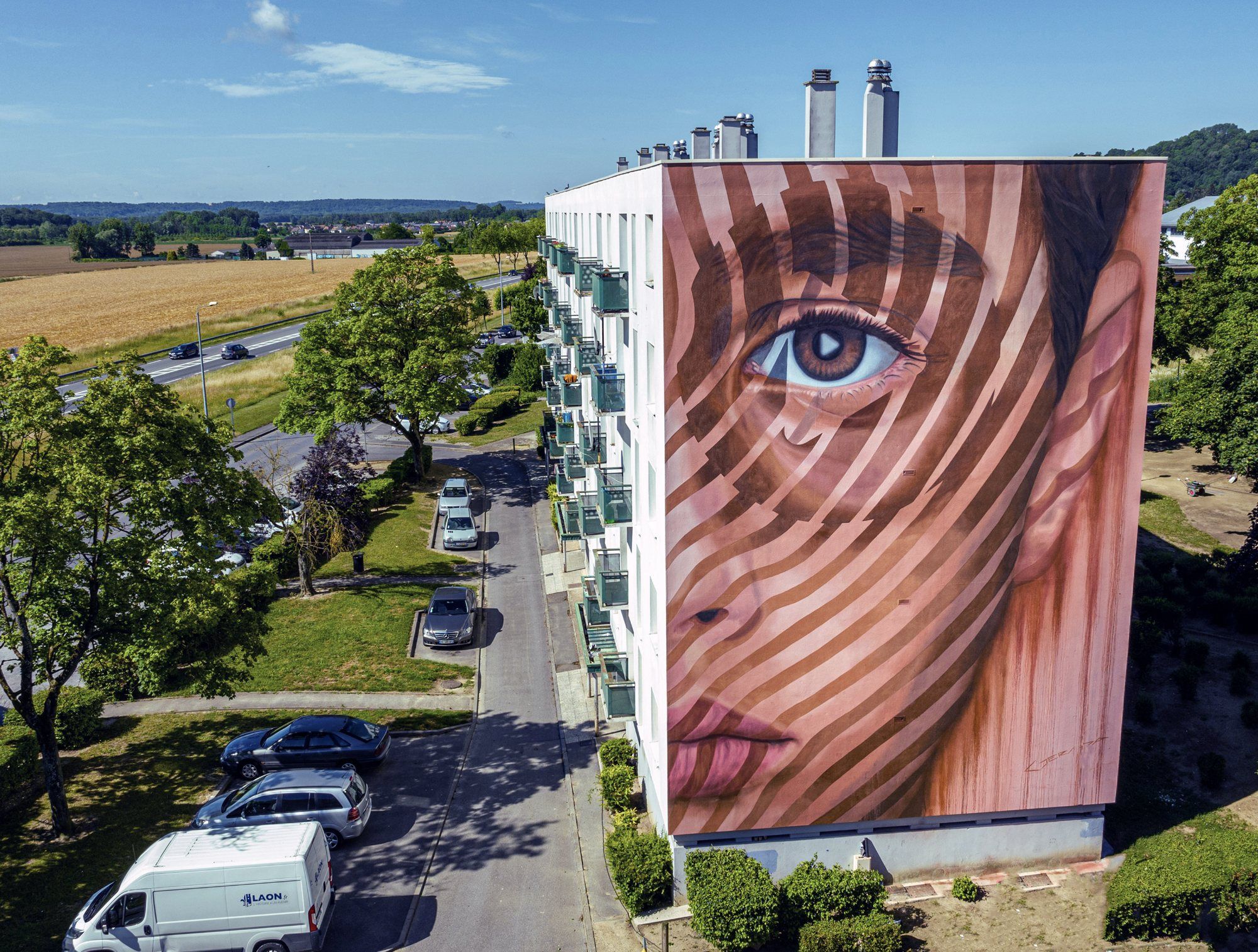 Outsight, a painted portrait mural covering the end wall of a residential building in Laon, France
