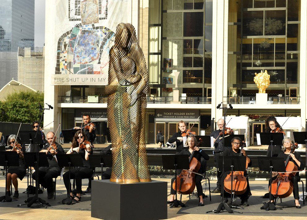 The Hug, a 10-foot bronze, at its unveiling outside Lincoln Center with a string ensemble